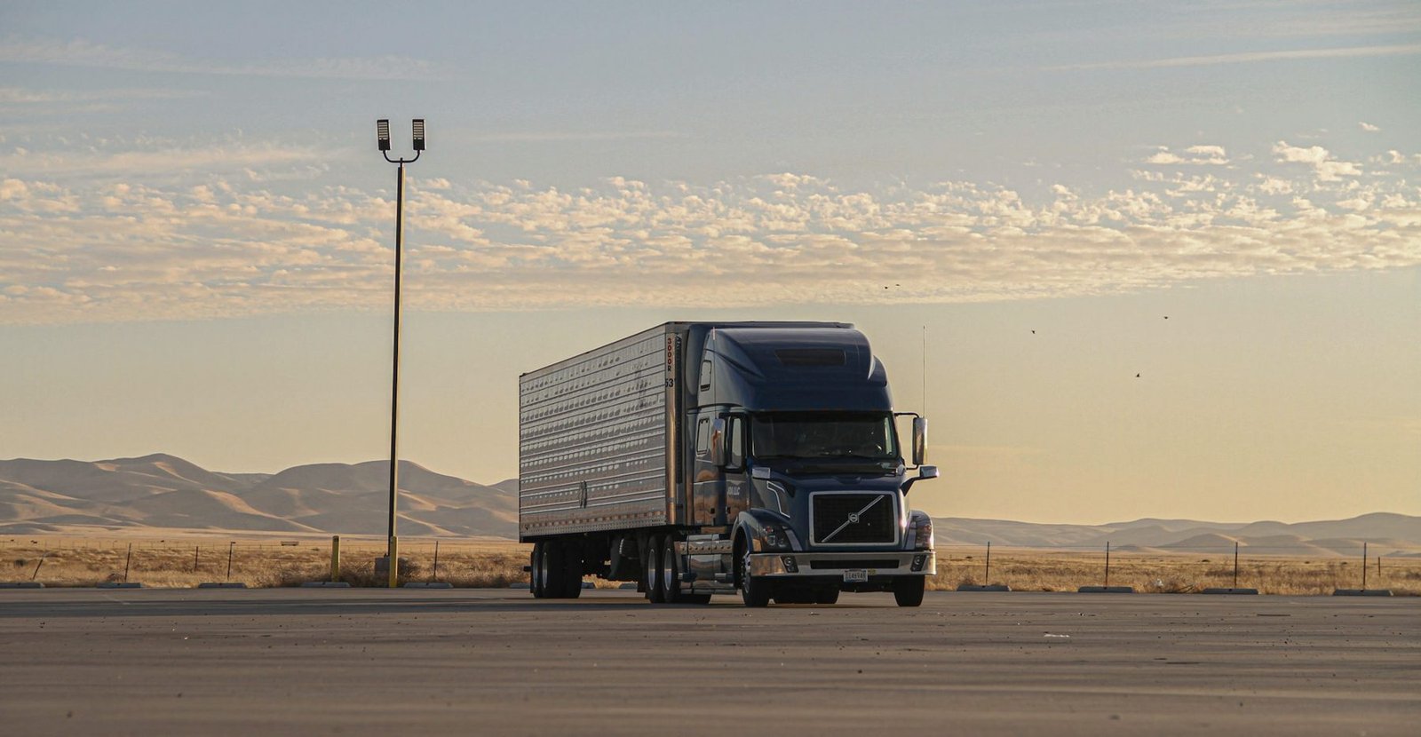 A semi tractor and trailer parked on an open lot at dusk